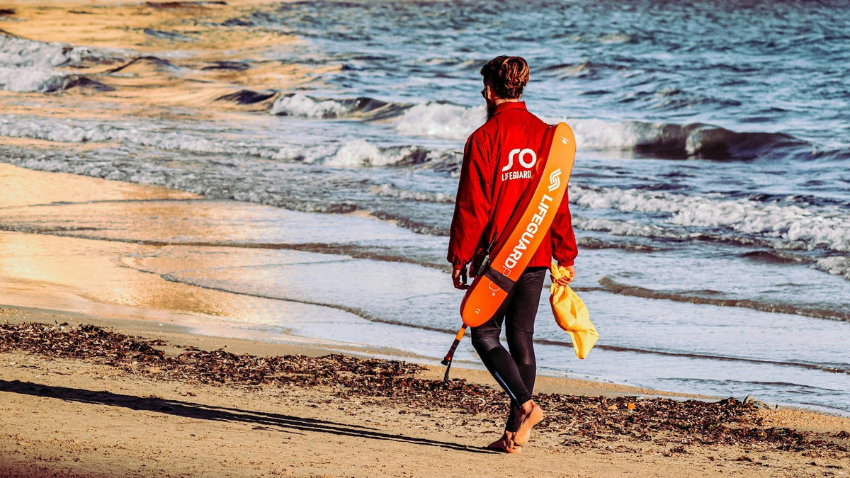 Surf, life and rescue worker walking on beach